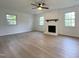 Living room with a brick fireplace, hardwood floors, and large windows offering views of the yard at 5817 Wintergreen Dr, Raleigh, NC 27609
