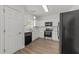 Well-lit kitchen features sleek black appliances, white cabinets, and quartz countertops at 620 Hanska Way, Raleigh, NC 27610