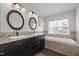 Bathroom featuring dual sinks, dark cabinetry, granite countertops, and a soaking tub at 703 Kirkeenan Cir, Morrisville, NC 27560