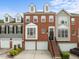 Charming brick townhome with a two-car garage, landscaped front yard, and inviting staircase entrance at 703 Kirkeenan Cir, Morrisville, NC 27560