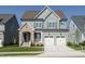 Charming two-story home showcasing beautiful stonework, a two-car garage, and a well-manicured lawn at 737 W Holly Springs Rd, Holly Springs, NC 27540