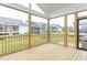 A screened-in porch with a wooden floor and a view of the backyard and neighboring homes at 743 W Holly Springs Rd, Holly Springs, NC 27540