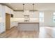 The open kitchen is complete with an island, modern lighting, and white cabinetry at 749 W Holly Springs Rd, Holly Springs, NC 27540