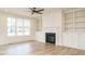Bright living room with modern ceiling fan, fireplace, built-in shelving and large window at 749 W Holly Springs Rd, Holly Springs, NC 27540