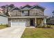 Charming two-story home with stone accents, a paved driveway, and a two-car garage at sunset at 8013 Toddwick Ct, Raleigh, NC 27616