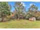 Lush backyard featuring mature trees, green grass, and a wooden storage shed at 8201 Rhodes Rd, Apex, NC 27539