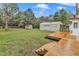 Backyard featuring a wooden deck, storage shed, large metal outbuilding, and lush greenery at 8201 Rhodes Rd, Apex, NC 27539