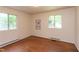 An airy bedroom features hardwood floors, neutral walls, and windows offering views of the outdoors at 107 Glosson Cir, Carrboro, NC 27510
