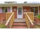 A charming brick home welcomes you with a wooden porch and a delightful white door at 107 Glosson Cir, Carrboro, NC 27510