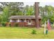 A single-story brick home showcases pink shutters and is complemented by a manicured lawn and mature trees at 107 Glosson Cir, Carrboro, NC 27510