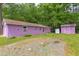 Backyard view of a purple garage with a small matching shed, accented by green foliage at 107 Glosson Cir, Carrboro, NC 27510