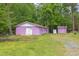 Backyard with vibrant purple garage and matching shed, offering ample storage and unique charm at 107 Glosson Cir, Carrboro, NC 27510