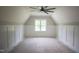 Unfinished attic space boasting paneling, a large window, vaulted ceilings, and a modern ceiling fan at 1108 Delilia Ln, Wake Forest, NC 27587