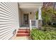 Close up shot of a front porch with a decorated door, white pillars, and red stairs at 1198 Shining Water Ln, Creedmoor, NC 27522