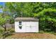 View of a white shed with a window and double doors, surrounded by greenery, in the backyard at 1198 Shining Water Ln, Creedmoor, NC 27522
