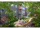 Building with landscaped backyard oasis featuring a patio with seating, surrounded by mature trees for privacy and shade at 130 Hunt St # 107, Durham, NC 27701