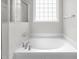 Relaxing bathtub with tile surround and a window providing natural light at 1307 Torrey Pines Ct, Mebane, NC 27302