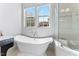 Bright bathroom with a soaking tub under a window and a glass enclosed shower at 1308 Green Oaks Pkwy, Holly Springs, NC 27540