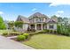 Charming two-story home features professional landscaping, stone accents, a covered porch, and a well-manicured lawn at 1308 Green Oaks Pkwy, Holly Springs, NC 27540