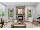 Cozy living room with stone fireplace, hardwood floors, natural light, and comfortable seating at 1308 Green Oaks Pkwy, Holly Springs, NC 27540