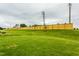 Large, well-manicured backyard with a new wooden fence and a stone fire pit in the distance at 1606 Garden Park Cir, Fuquay Varina, NC 27526