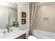 Bathroom showcasing granite counters, wood-look cabinets, and a tub shower with a decorative shower curtain at 1606 Garden Park Cir, Fuquay Varina, NC 27526