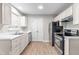 Bright kitchen featuring modern appliances, white cabinetry, and durable laminate flooring at 1628 Briarmont Court Ct, Raleigh, NC 27610