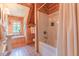 Cozy bathroom with wood paneled walls and window with seat above pedestal sink and bathtub at 169 Country Brooke Lane Ln, Roxboro, NC 27574