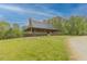 Charming metal-roof home with stone chimney featuring a covered porch overlooking a beautifully landscaped lawn at 169 Country Brooke Lane Ln, Roxboro, NC 27574