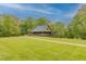 Scenic view of a well-maintained country estate with a charming metal-roof home, and a vast green lawn at 169 Country Brooke Lane Ln, Roxboro, NC 27574