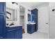 Modern bathroom featuring blue cabinetry, marble countertops, and illuminated mirrors at 1903 Edgerton Dr, Durham, NC 27703