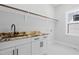 Bright laundry room with white cabinets, granite countertop, and a stainless steel sink at 1903 Edgerton Dr, Durham, NC 27703