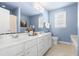 Bright bathroom featuring double vanity sinks, a large mirror, and neutral tile flooring at 210 Millet Dr, Morrisville, NC 27560