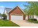 Charming brick home featuring an attached garage, well-manicured lawn, and solar panels on the roof at 210 Millet Dr, Morrisville, NC 27560