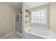 Bathroom with a glass shower and a soaking tub beneath a window with decorative shelves at 2429 Follow Me Way, Raleigh, NC 27610