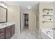 Bright bathroom featuring double sinks, a glass shower, a soaking tub, and decorative shelves at 2429 Follow Me Way, Raleigh, NC 27610