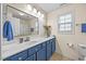 Bathroom with blue cabinets under a sink with a mirror and natural light at 2429 Follow Me Way, Raleigh, NC 27610
