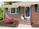 Close-up of a charming brick home entrance with a well-manicured yard and bright plantings at 2702 Richwood Rd, Durham, NC 27705