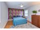 Vibrant bedroom showcasing a colorful accent wall, hardwood floors, and a ceiling fan for added comfort at 2811 Van Dyke Ave, Raleigh, NC 27607