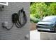 Close up of wall mounted EV charger and cord with a car parked in the driveway at 2811 Van Dyke Ave, Raleigh, NC 27607