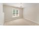 Cozy bedroom with neutral walls and carpet features a window and an elegant hanging chandelier at 315 Copper Ridge Dr, Sanford, NC 27330