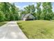 Single-Gathering home features a spacious driveway and verdant lawn, bordered by dense, mature trees at 315 Copper Ridge Dr, Sanford, NC 27330
