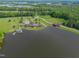Wide aerial view of a lakefront property with lush surroundings, boat dock, and access bridge at 325 Forest Bridge Rd, Youngsville, NC 27596
