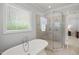 Bathroom with a glass-enclosed shower, soaking tub, and a bright window at 325 Forest Bridge Rd, Youngsville, NC 27596