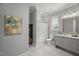 Bright bathroom with marble floors, gray vanity, decorative painting, and shower-tub combination at 325 Forest Bridge Rd, Youngsville, NC 27596