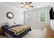 Bedroom features a bed with floral accents, a ceiling fan, two large windows, and a mounted TV at 325 Forest Bridge Rd, Youngsville, NC 27596