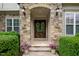 Close-up of the front door, featuring stone archway, decorative wreaths, and landscaped surroundings at 325 Forest Bridge Rd, Youngsville, NC 27596