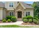 Charming home featuring an arched entryway, stone accents, and lush, landscaped garden at 325 Forest Bridge Rd, Youngsville, NC 27596
