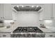 Close-up of a professional stove and hood in a modern kitchen with tile backsplash at 325 Forest Bridge Rd, Youngsville, NC 27596