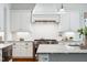 This kitchen features white cabinets, stainless steel appliances, a decorative hood, and a marble countertop island at 325 Forest Bridge Rd, Youngsville, NC 27596